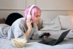 vrouw vermaakt zich online op laptop met schaal popcorn