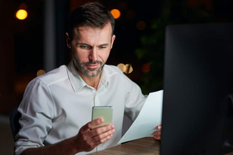 man houdt mobiel vast en een papier