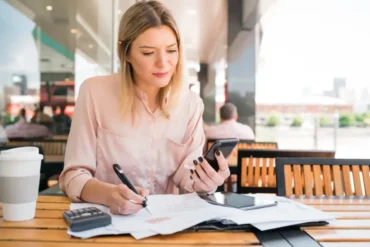 Vrouw doet administratie met rekenmachine en mobiel
