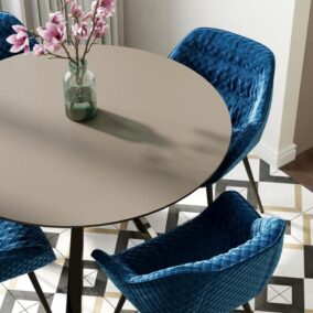 ronde eettafel met vier blauwe fluwelen stoelen en magnolia takken in vaas