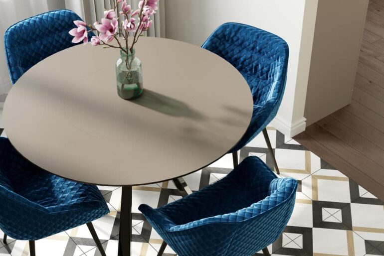 ronde eettafel met vier blauwe fluwelen stoelen en magnolia takken in vaas