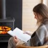 vrouw leest boek bij houtkachel