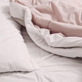 Roze dekbed en wit hoofdkussen op bed