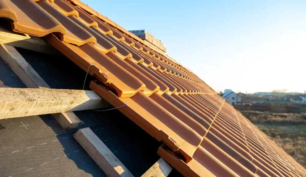 Oranje dakpannen op een hellend dak in zonlicht.