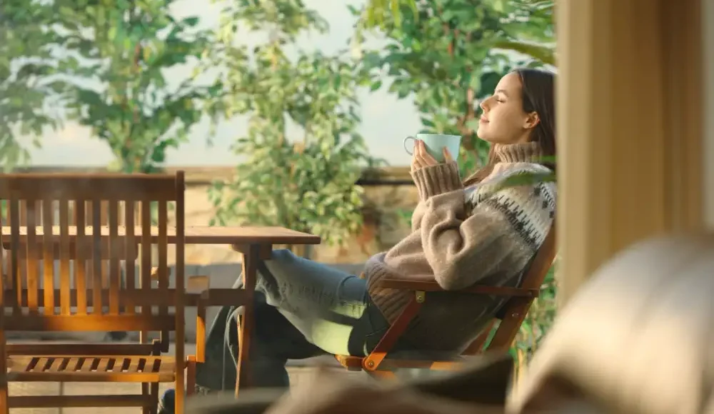 Vrouw ontspant buiten in tuin met warme drank.