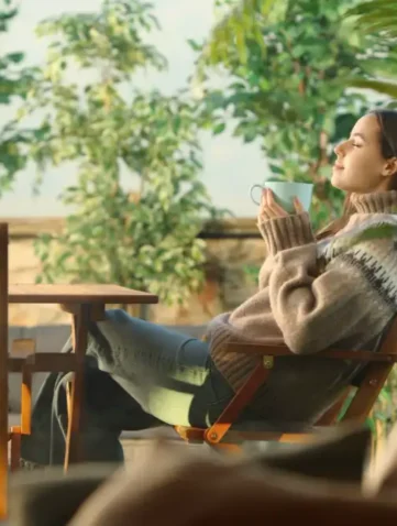 Vrouw ontspant buiten in tuin met warme drank.