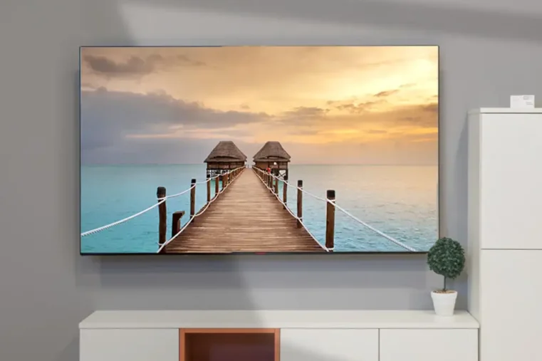 Grote TV in woonkamer met beeld van zonsondergang bij pier over oceaan