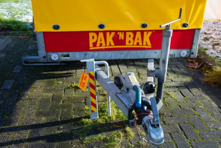 Ongesloten aanhanger op parkeerplaats met PAK 'N BAK logo.