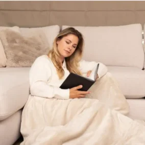 vrouw zit warm voor de bank met deken en kussens