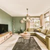 Stijlvolle zithoek met bank, tv en groene muren.