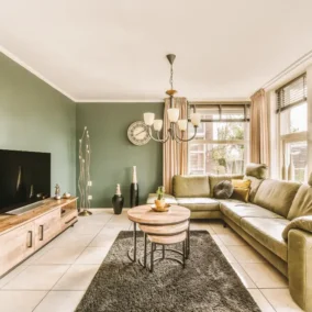 Stijlvolle zithoek met bank, tv en groene muren.