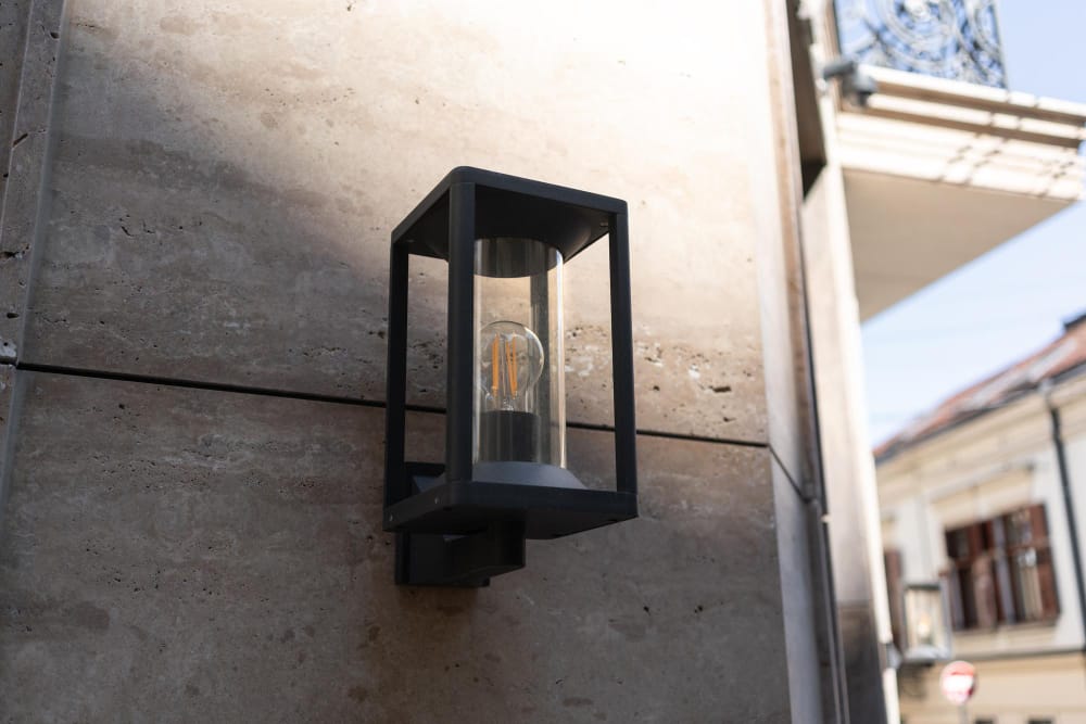 Moderne buitenlamp aan stenen muur in zonlicht.