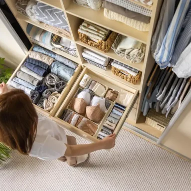 Vrouw organiseert netjes ingedeelde kledingkast met lades