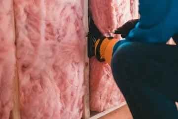man met handschoenen brengt isolatie aan