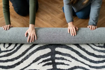 twee mensen rollen vloerkleed op