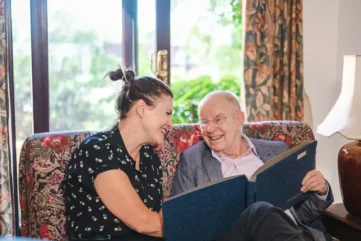 oudere man bekijkt fotoalbum met jongere vrouw