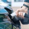 Hand steekt stekker in elektrische auto.