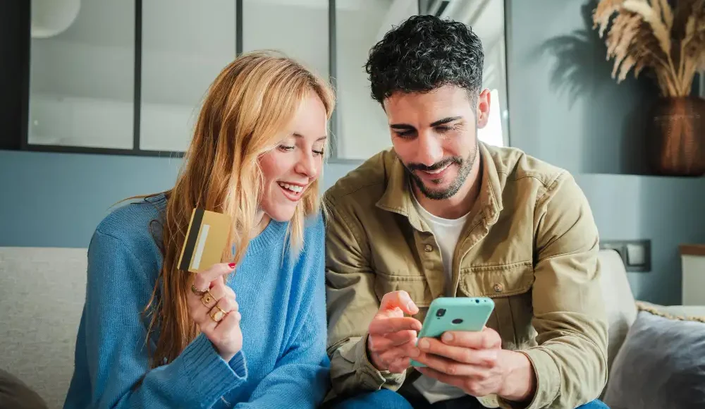 vrouw met bankpas kijkt samen met man op mobiele telefoon