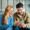 vrouw met bankpas kijkt samen met man op mobiele telefoon