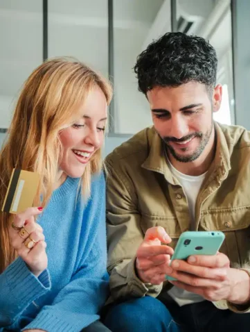 vrouw met bankpas kijkt samen met man op mobiele telefoon