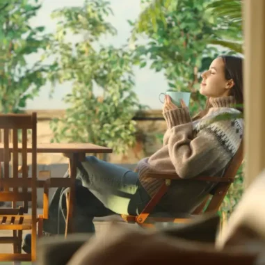 Vrouw ontspant buiten in tuin met warme drank.