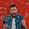 Blije man viert jackpot met confetti en smartphone