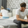 Man en vrouw zitten op bed met de rug naar elkaar toe.