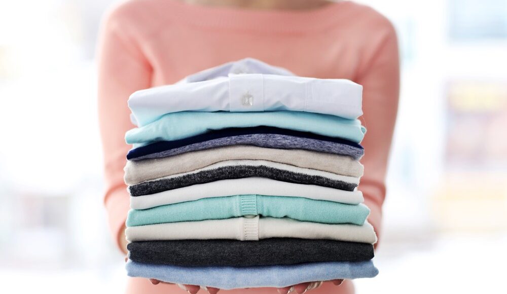 vrouw houdt stapel gevouwen kleding vast