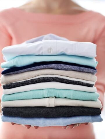 vrouw houdt stapel gevouwen kleding vast